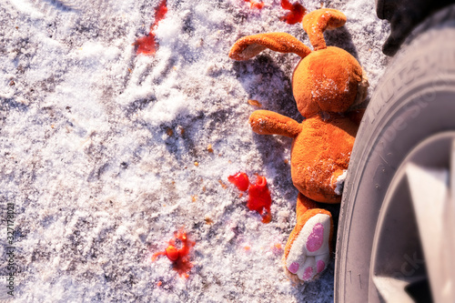 children's accident on a winter road, Bunny rabbit toy. Death on the road, carelessness and danger. Attention and caution. roadkill winter, blood on snow. Concept, copy space