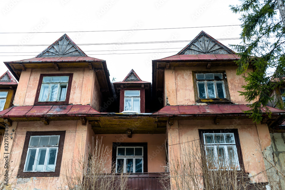 Old destroyed and abandoned house with roof windows and broken one glass, standing by the main road in the city.