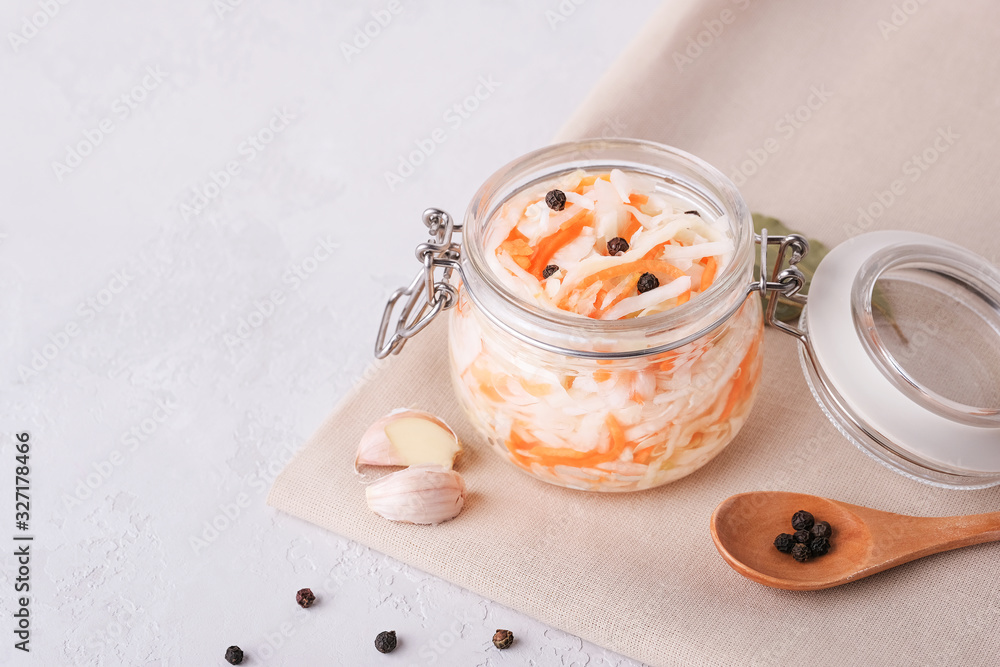 Glass jar with homemade sauerkraut, black pepper on a gray table. Copy space Glass jar with homemade sauerkraut, black pepper on a gray table. Copy space