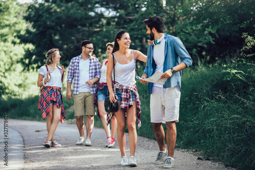 Group of young people with backpacks walking together by the road and looking happy