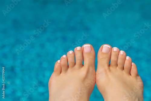 beautiful legs with french pedicure on the background of the pool