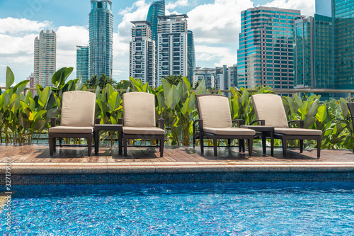 Photography sun loungers by the rooftop pool against the background of Kuala Lumpur skyscrap