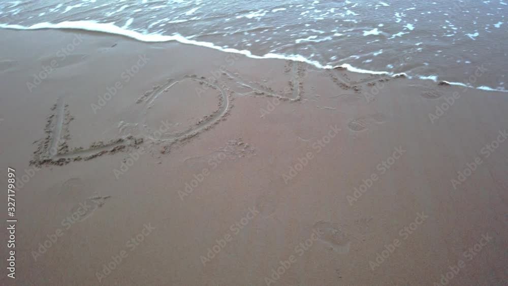 wave spreading on the beach became a sea foam. background and texture.word love on sand are erasing by water wave spreading on the beach became a sea foam. background and texture.word love on sand are erasing by water