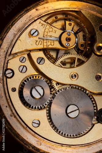 Close up of an authentic 100 hundred years old pocket watch mechanism cogs and wheels , golden