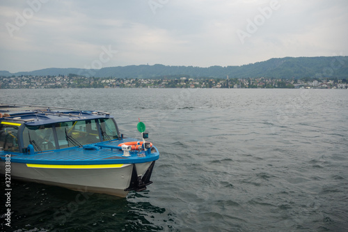 Colorful ferryboat stops for passengers at the pier in Limmat river with cloudy sky , background , copy space , Switzerland