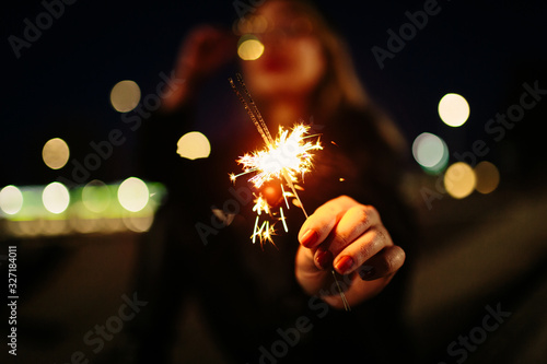 Young blonde girl with glasses plays at night with a fireworks candle