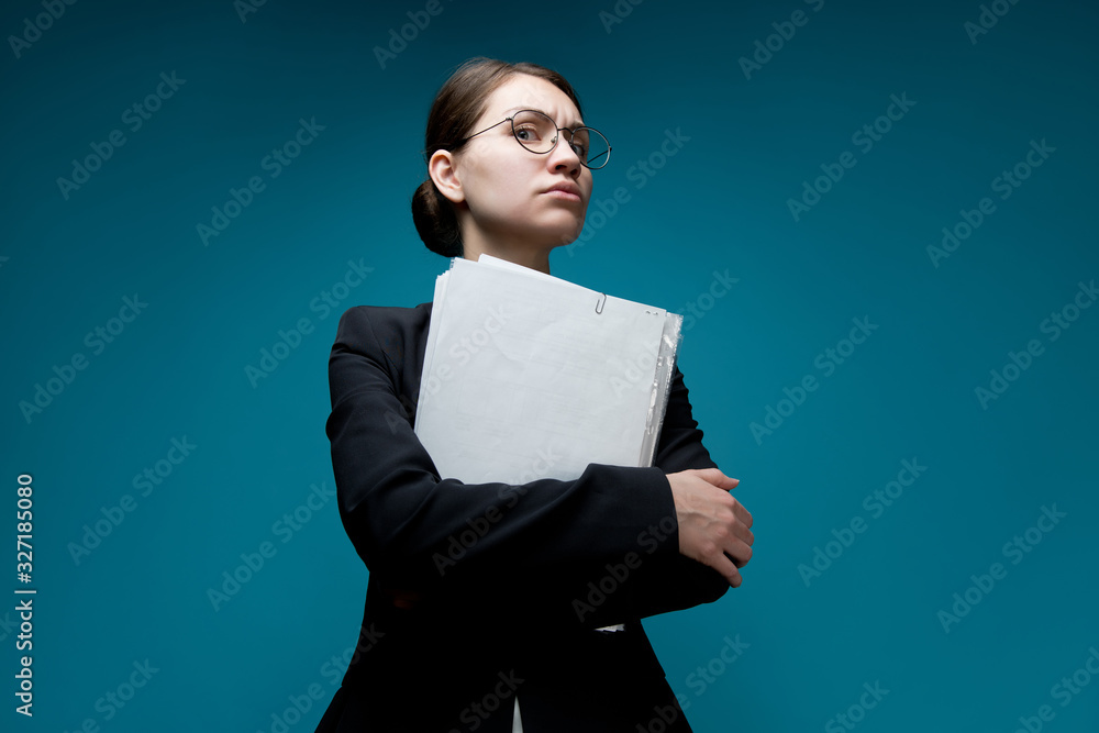 A young woman with glasses looks down with anger at the camera, holding documents. Female boss A young woman with glasses looks down with anger at the camera, holding documents. Female boss