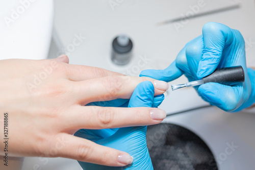 Master in beauty salon applyes a nail polish to client's finger nail. © Galina_lya
