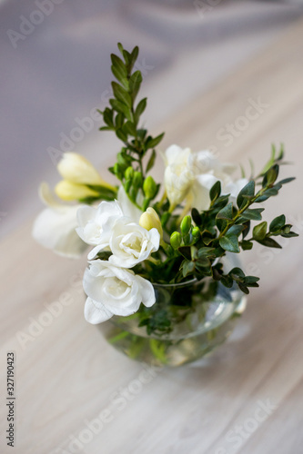 white freesia flowers in a spherical glass vase