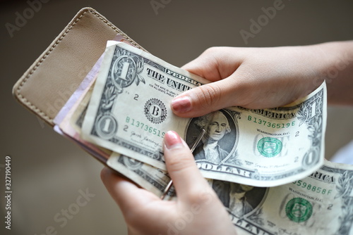 A girl picks a one dollar banknote from her clip wallet