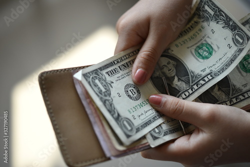 A girl picks a one dollar banknote from her clip wallet
