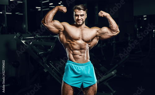 Bodybuilder strong man pumping up biceps muscles