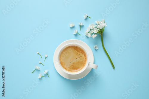 White flowers and coffee on light blue background, flat lay. Good morning