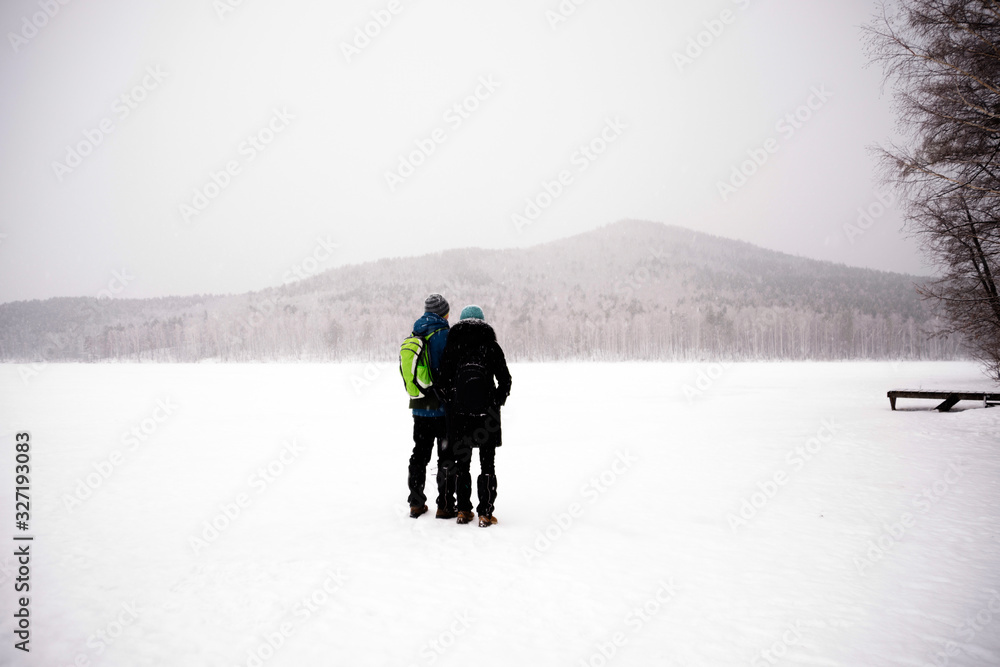 Two tourists with backpacks on the background of snowy mountains. Trourism, sports recreation.