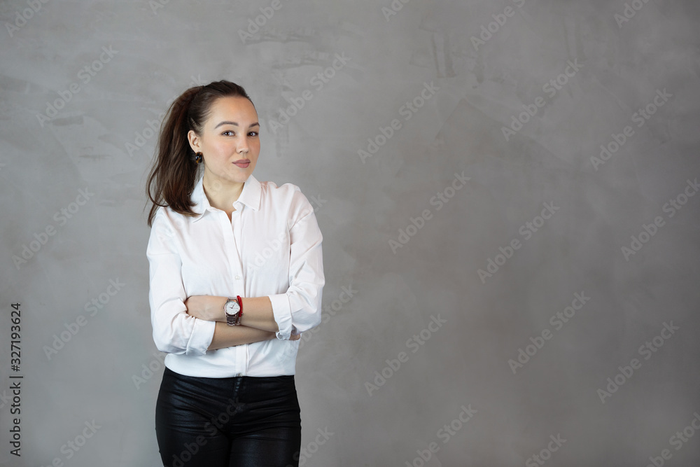 young Business woman in white shirt standing with crossed arms on gray background copy space young Business woman in white shirt standing with crossed arms on gray background copy space