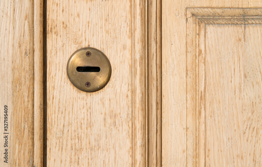 Flat keyhole on an old tan shabby retro door. Vintage beige peach color door with a horizontal keyhole. Bronze or brass pad on the castle well Flat keyhole on an old tan shabby retro door. Vintage beige peach color door with a horizontal keyhole. Bronze or brass pad on the castle well