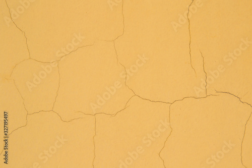 A dark yellow  plastered painted background with several small  subtle cracks. Old vintage orange surface. Cracked plaster