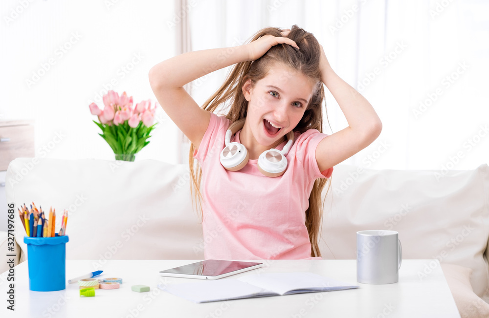 Cute little girl with blank tablet computer holding her head and screaming in the living room Cute little girl with blank tablet computer holding her head and screaming in the living room