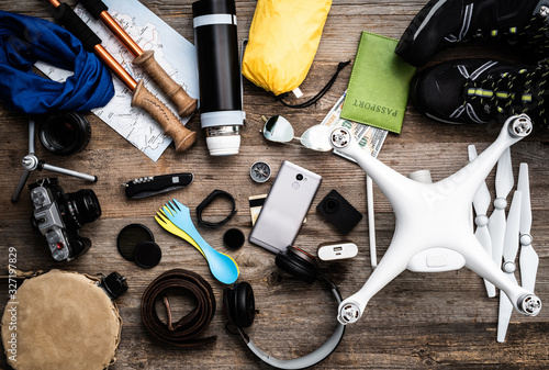 Various travel accessories with flashlight and other tools on the wooden table, top view.