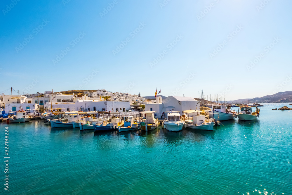 Fishboats and yachts moored in Naoussa port, Paros island, Greece. View on dock for boats and yachts at bright sunny day