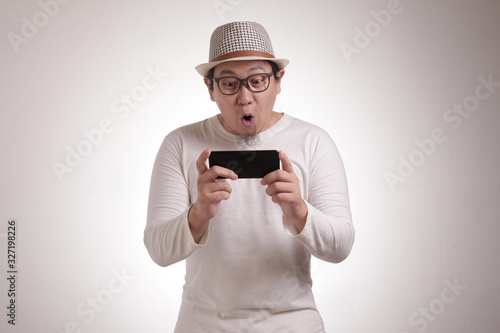 Funny Young Asian Guy Playing Games on Tablet Smart Phone © airdone