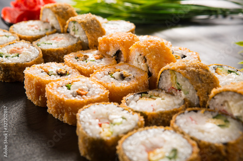 Set of baked sushi rolls with wasabi and ginger on a black background. Japanese oriental cuisine