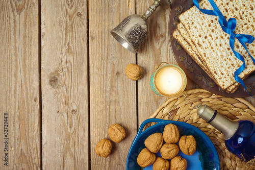 Jewish holiday Passover background with matzo, seder plate and wine on wooden table.