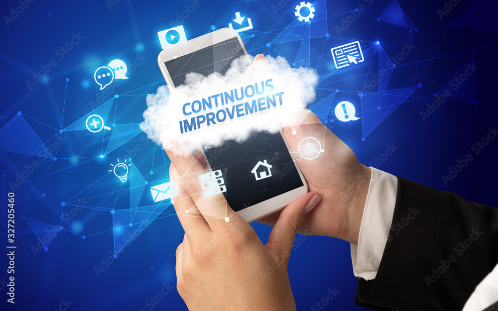 Female hand holding smartphone with CONTINUOUS IMPROVEMENT inscription, cloud technology concept Female hand holding smartphone with CONTINUOUS IMPROVEMENT inscription, cloud technology concept