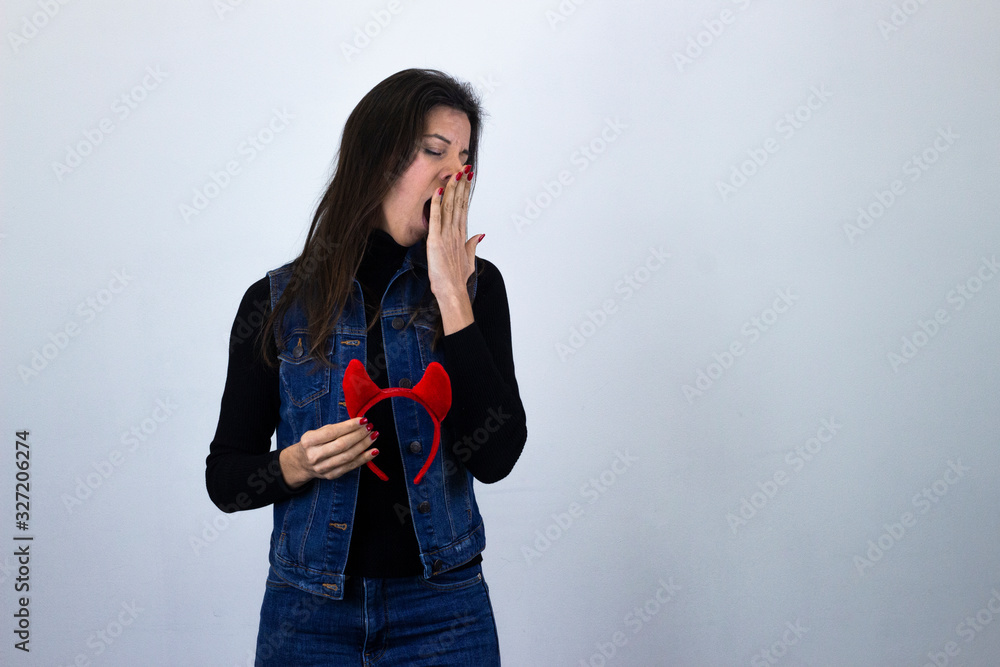 Bosteza durmiendose calm and cute bussiness womandevil hornscovers mouth with hand, yawns sleeping with closed eyes, isolated on gray background studio shot, black sweater, denim jacket, jeans, dark a Bosteza durmiendose calm and cute bussiness womandevil hornscovers mouth with hand, yawns sleeping with closed eyes, isolated on gray background studio shot, black sweater, denim jacket, jeans, dark a