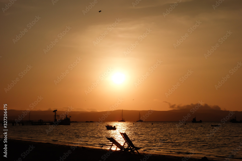 sunset reflecting on the sea. Boats in the beach of Paracas/Peru.