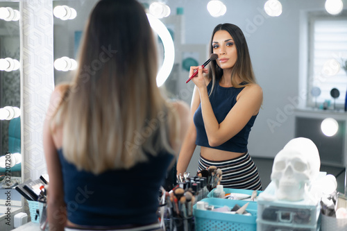 Portrait of pretty female beautician standing posing at workplace in hair and beauty salon