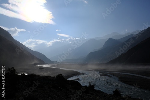 The riverbed of the Kali Gandaki River near Jomson in the land of Mustang in Nepal. Dust floating in the glare of the sun in strong gusts of wind. During trekking around Annapurna, Annapurna Circuit