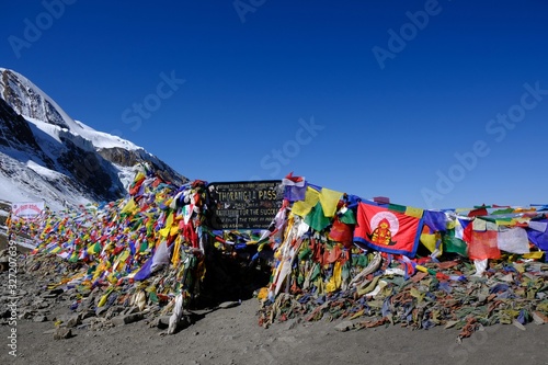 Plaque with inscription and prayer flags on Thorong La Pass (5416 m) in Himalayas. This is  the highest place during trekking Annapurna Circuit photo