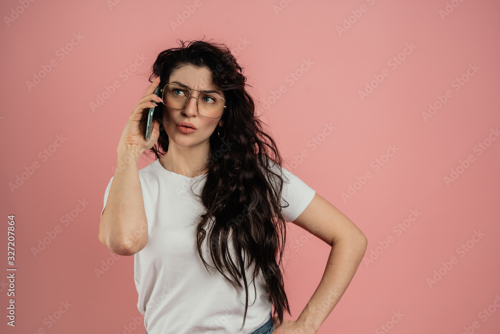 Fototapeta premium The girl speaks on the phone, portrait on a pink background