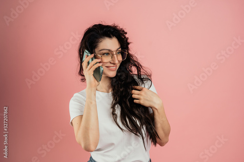 The girl speaks on the phone  portrait on a pink background