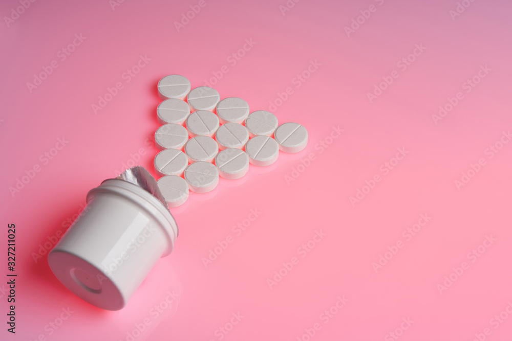 White round tablets scattered near plastic bottle of pills White round tablets scattered near plastic bottle of pills