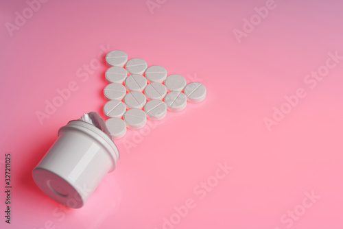 White round tablets scattered near plastic bottle of pills