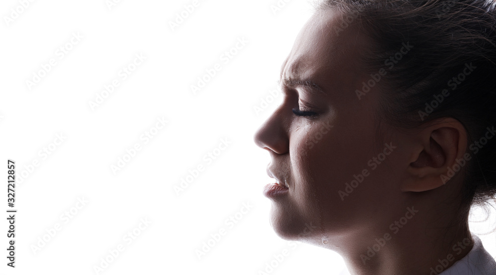 Beautiful young sad woman crying with closed eyes. White background. Free space for text. Tear on cheek of unhappy female.