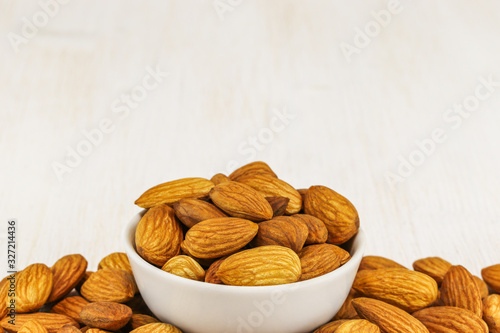 Almonds in a white bowl and on a white background