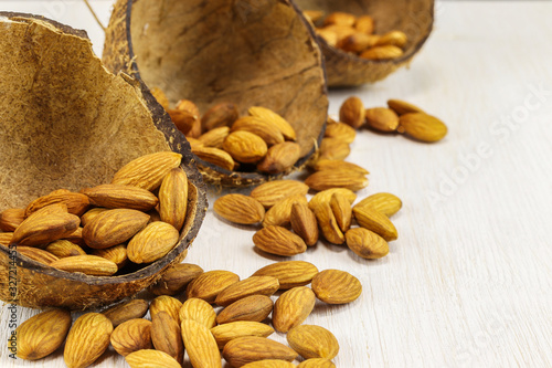 Almonds in half a coconut shell and on a white background