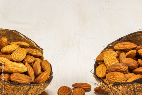 Almond nuts in two half coconut on a white background