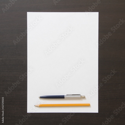 Template of white paper with pen and pencil on dark wenge color wooden background.