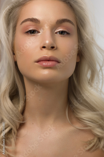 Closeup portrait of a woman with developing straight hair. Sweet tender young girl blonde. Natural lipstick, transparent clean skin. Skin care natural cosmetics in the spa salon or cosmetology.