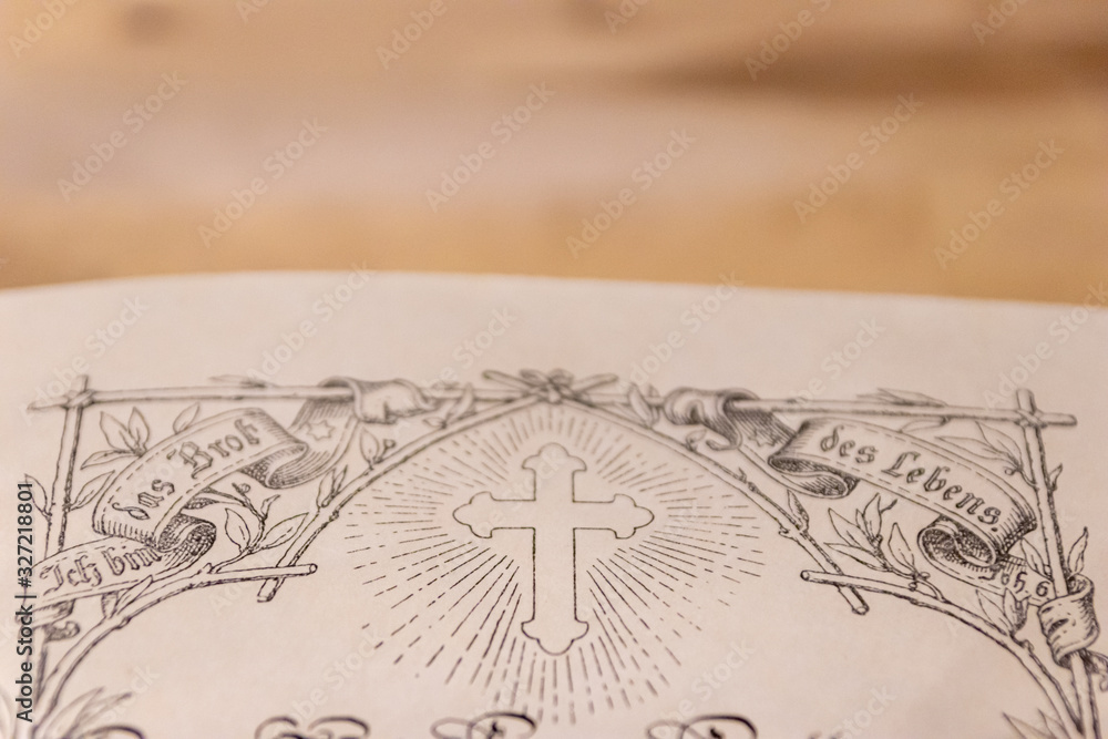 Fototapeta premium Kreuz einer geöffneten antiken Lutherbibel zeigt die evangelische Kirche und Übersetzung von Martin Luther mit einer verzierten Ausgabe der Bibel von 1914