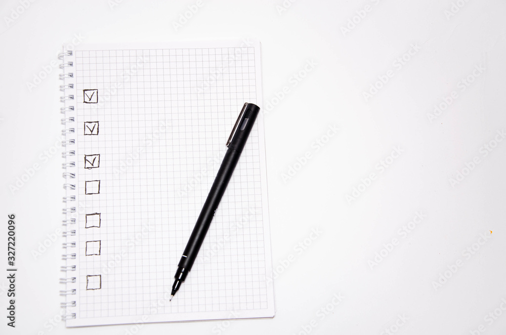 Check list. Square items are empty and checked with a tick. Squared notebook with black pen on a white background. Record ideas, notes, plans, tasks. Copy Space Check list. Square items are empty and checked with a tick. Squared notebook with black pen on a white background. Record ideas, notes, plans, tasks. Copy Space