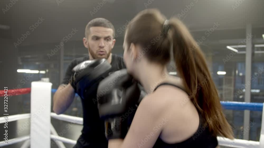 Young woman boxing with coach in gym Young woman boxing with coach in gym