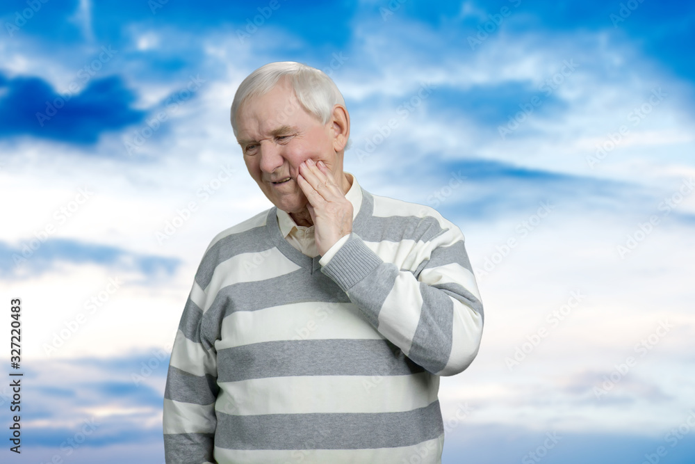 Old grandfather with toothache. Sick senior man in striped sweater. Blue sky background. Old grandfather with toothache. Sick senior man in striped sweater. Blue sky background.