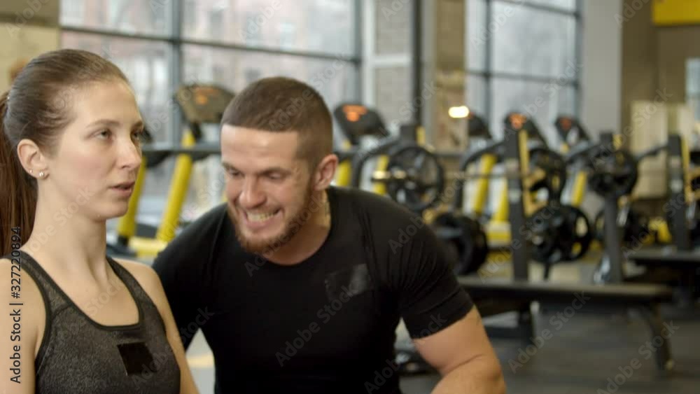 Young woman working out in gym under the supervision of instructor Young woman working out in gym under the supervision of instructor