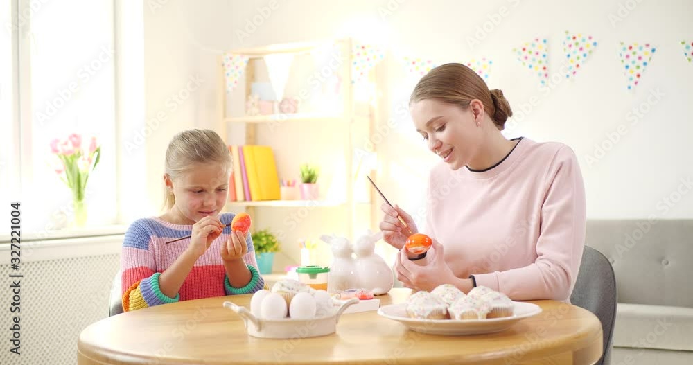 Happy mother and daughter painting eggs for Easter celebration at home Happy mother and daughter painting eggs for Easter celebration at home