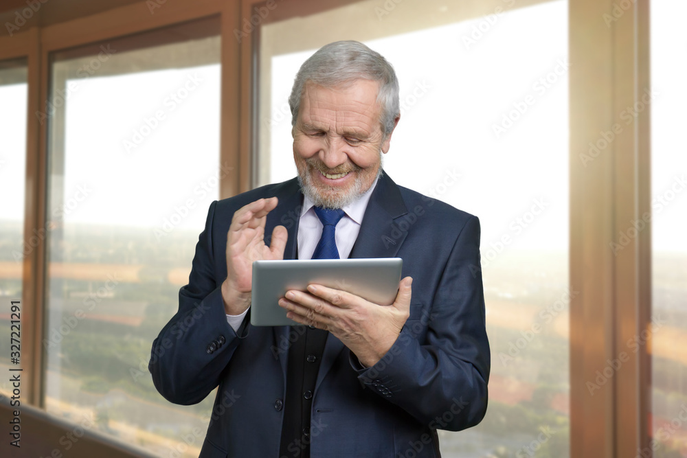 Fototapeta premium Old successful happy businessman with tablet. Smiling man using gadget, windows background.